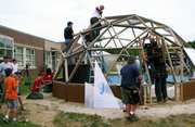 people building a geodesic dome greenhouse from afar