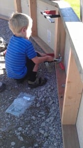 Young boy helping construct his family greenhouse
