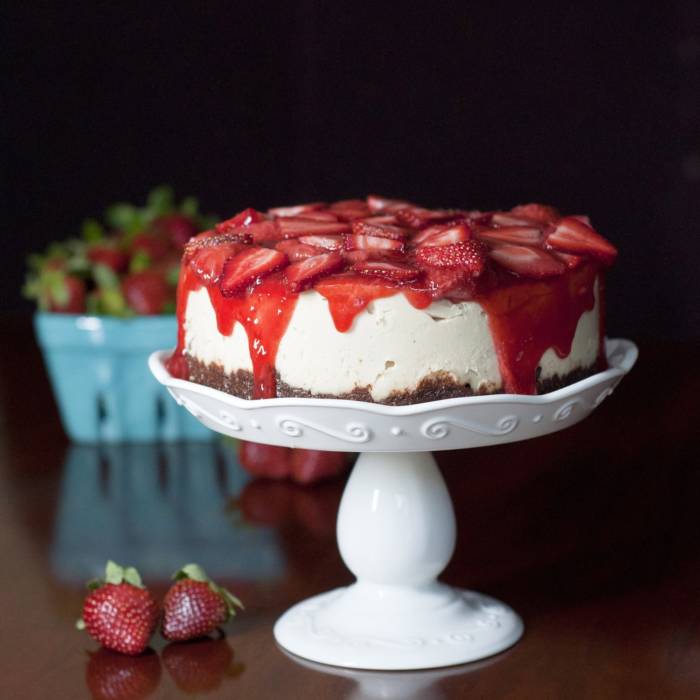cheesecake on cake stand with fresh cut strawberries on top