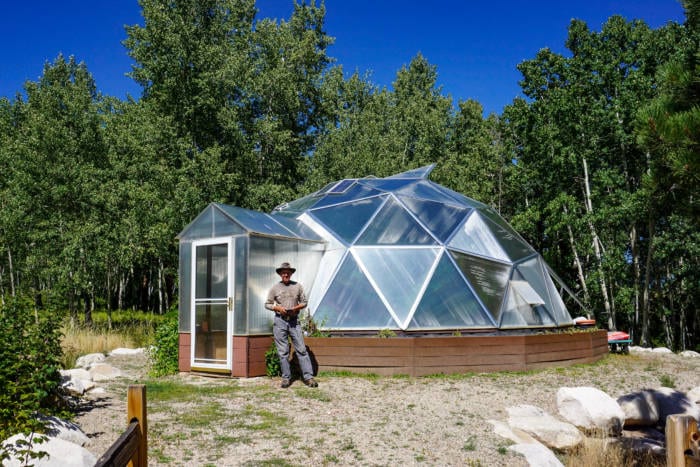 outside view of a growing dome with a screen door and a person standing next to it