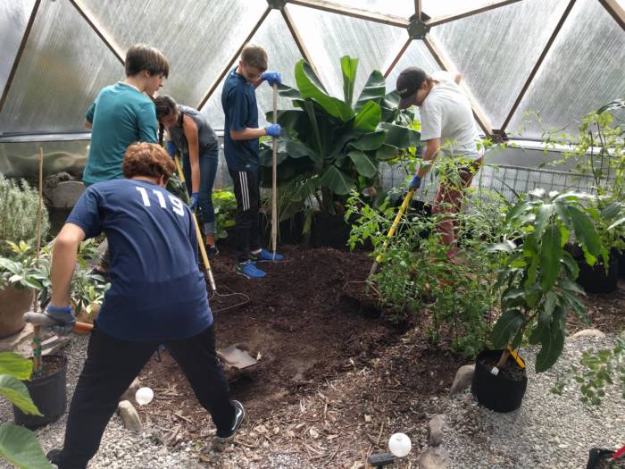 students planting in biodome tropical greenhouse