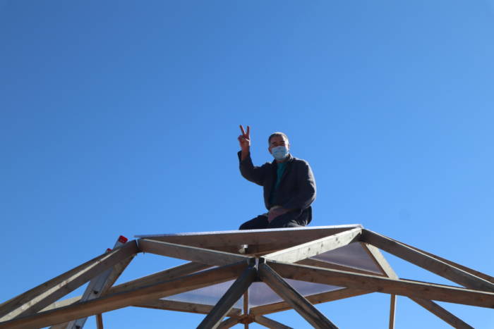 man with peace sign on top of growing dome under construction