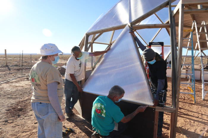 team attaching glazing panels to greenhouse
