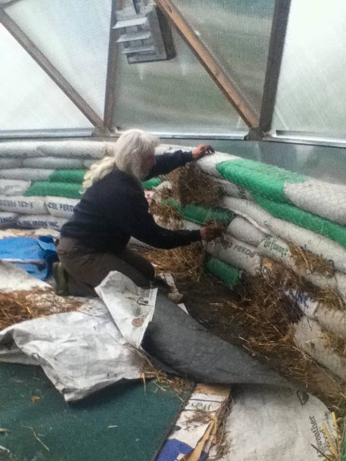 woman building concrete raised beds in a greenhouse in Alaska