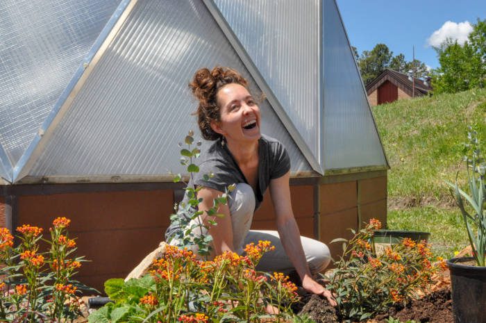 Gardener planting flowers outside a greenhouse to attract pollinators