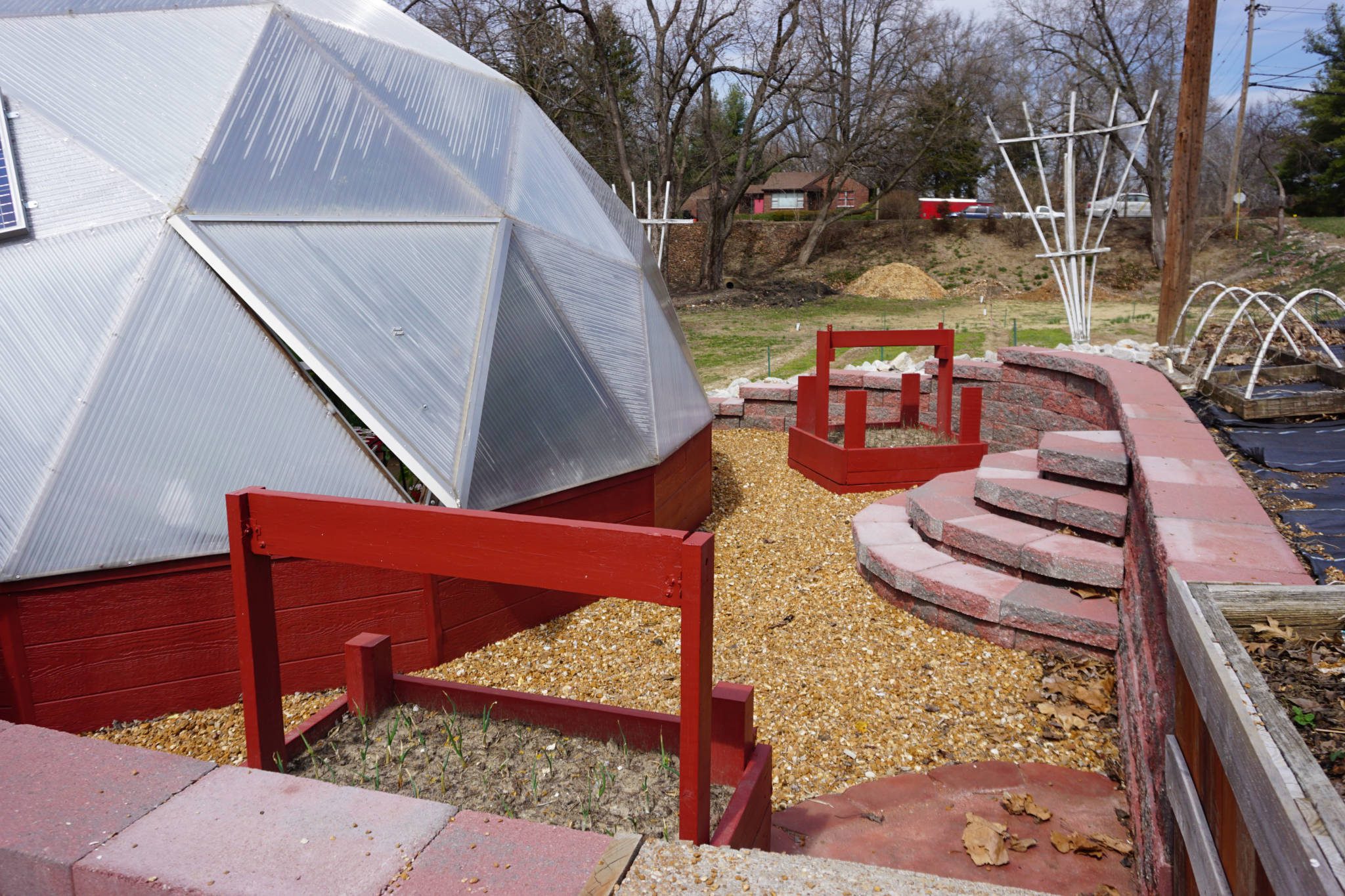 red raised beds outside of a dome greenhouse
