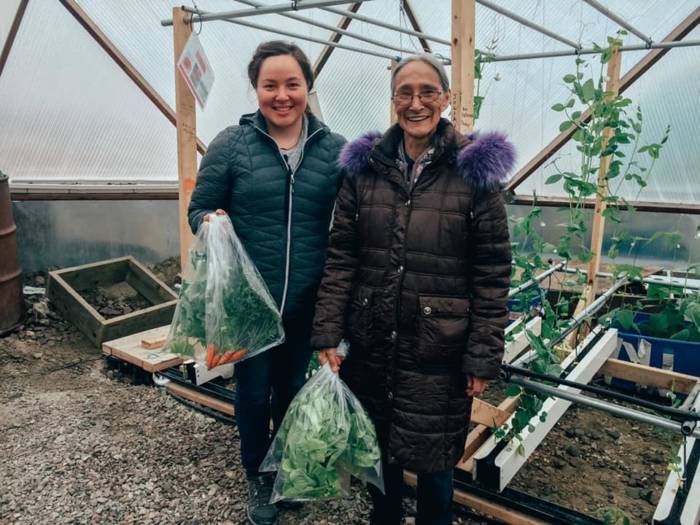 Community members with fresh greenhouse produce