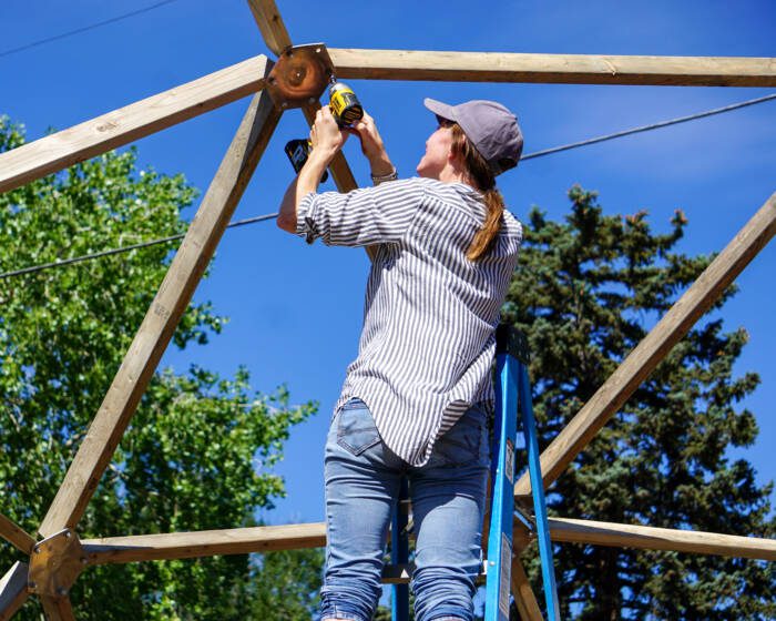 Young lady learning how to build a geodesic dome greenhouse from growing spaces during a volunteer event for go farm in golden, CO. 