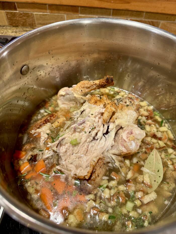 Cooking leftover turkey soup in a pot. Demonstrating how much liquid to add for a proper soup