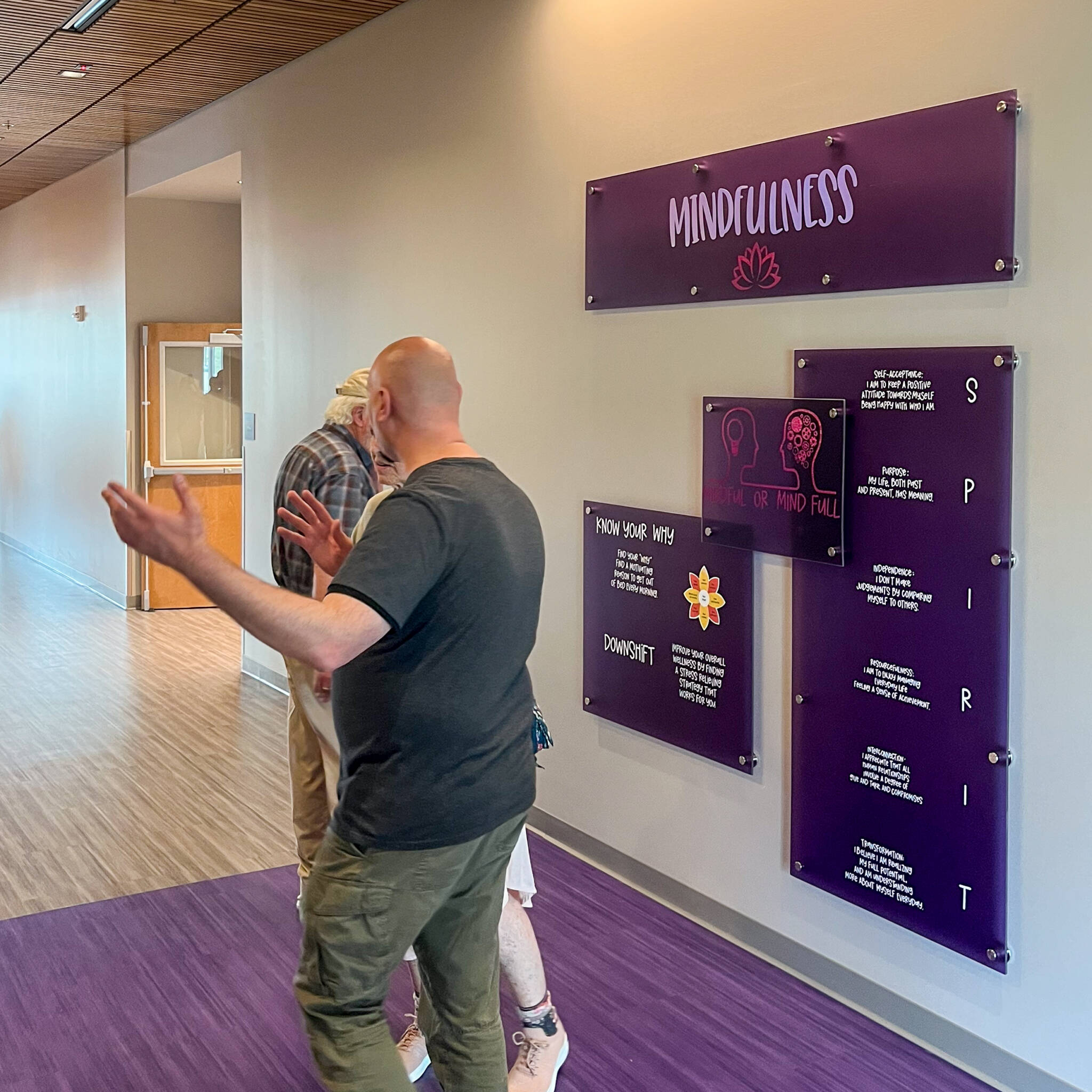 Employee showing visitors signage explaining the importance of mindfulness at the wellness center.