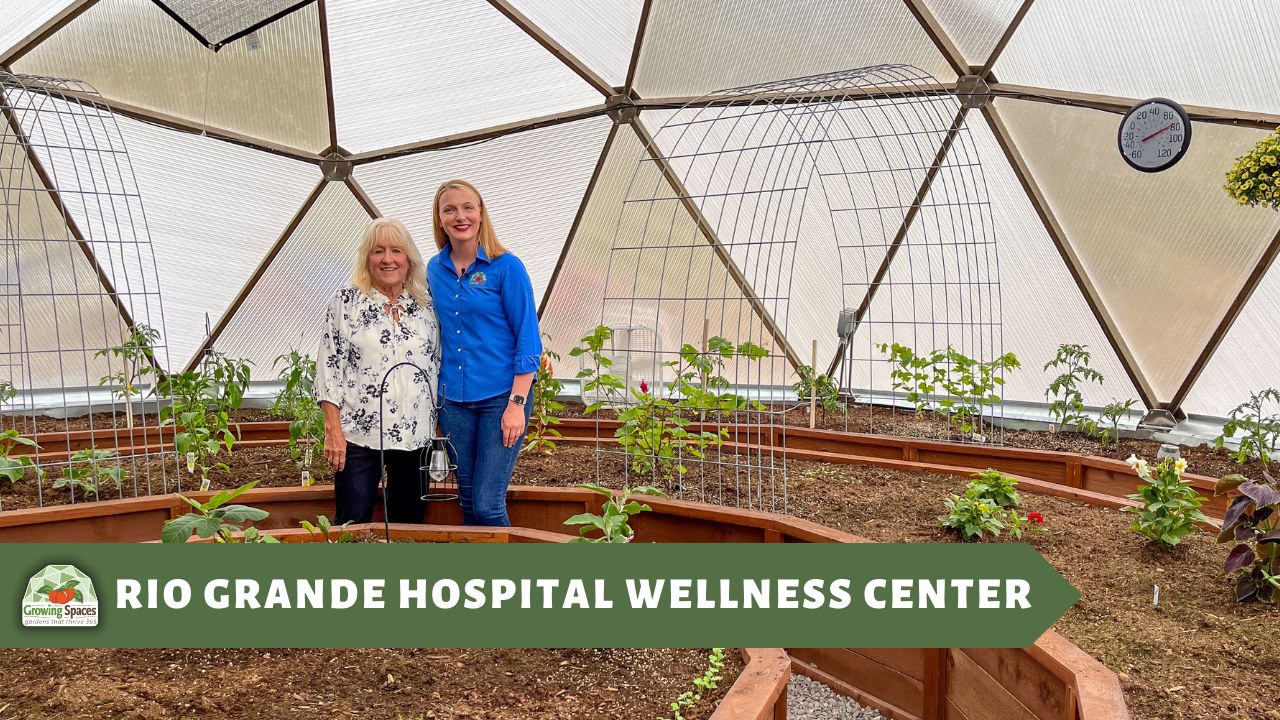 two women stand together inside a newly planted Growing Dome smiling and looking at the camera